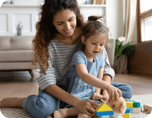 A nanny from a Nanny For U engaging with a small child's creativity using colorful wooden blocks.