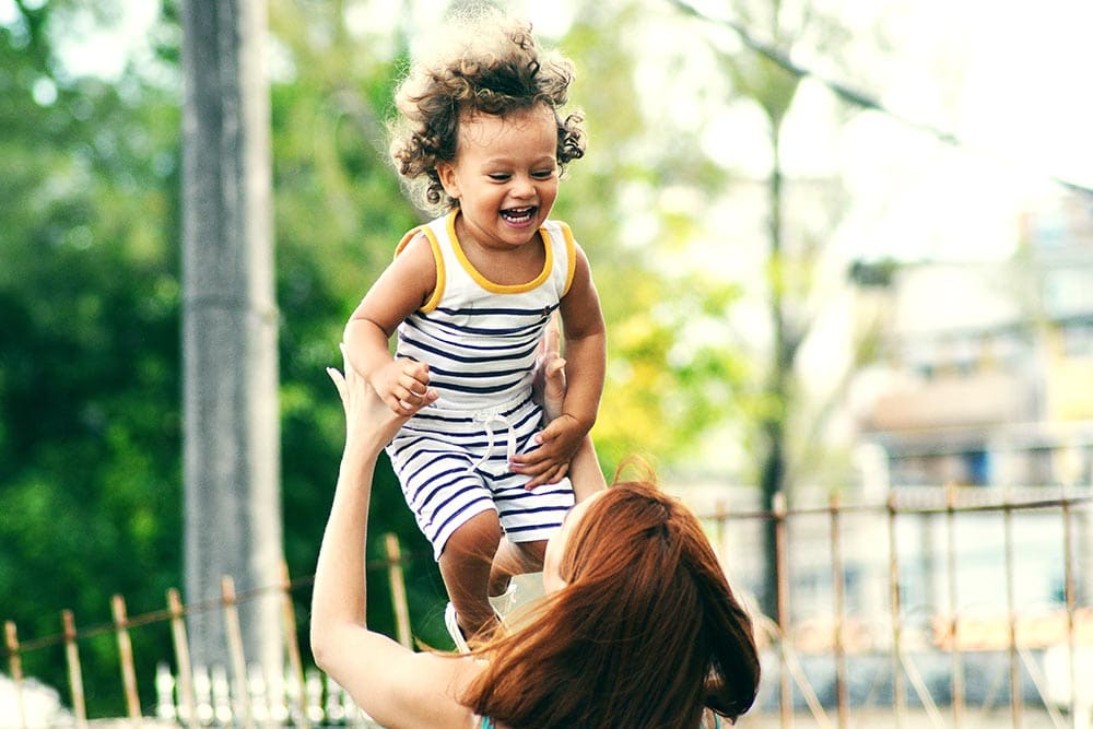 A nanny playing with a child outside.