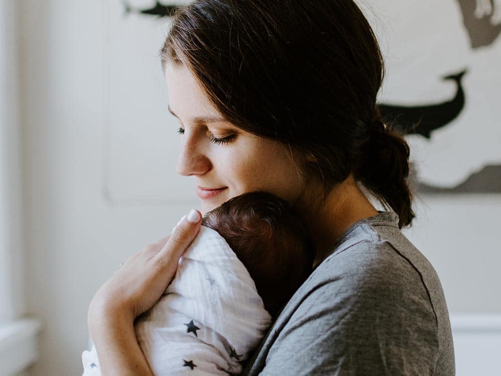 A newborn care specialist comforting a newborn baby.